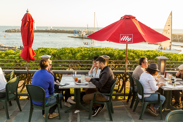 Groups of people eating at the Crow's Nest outdoor patio that overlooks the ocean. 