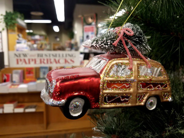 Ornament of a glitter red station wagon with a Christmas tree on top, tied with a pink string. This can be found at Bookshop Santa Cruz