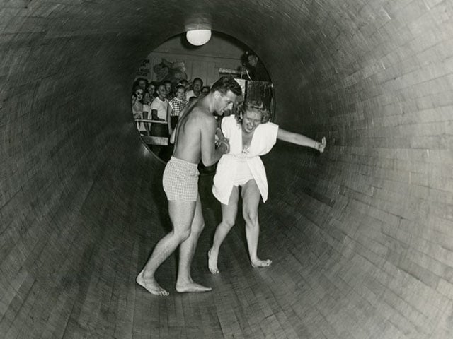 SC Boardwalk black and white image of rotating barrel attraction, man and woman