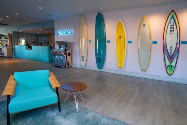 Dream Inn lobby with teal cahir and wall of o'neill surfboards.