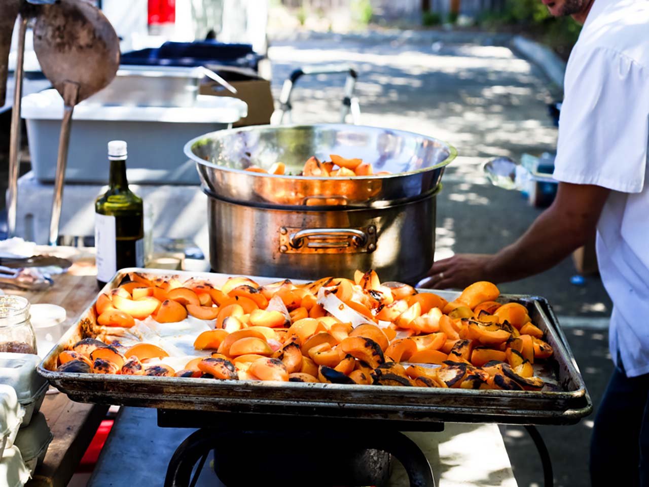 An outdoor chef lightly grilling peaches.
