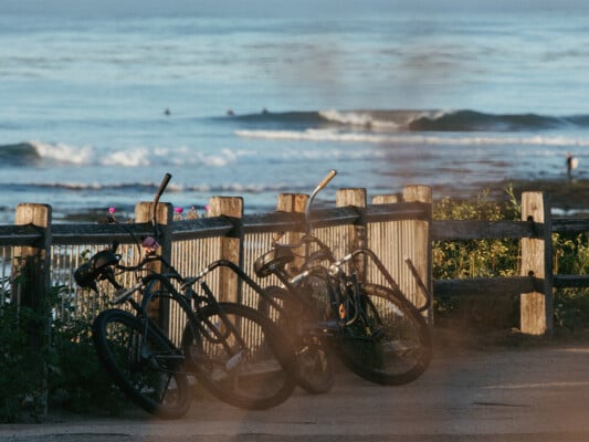 Bikes with surfboard racks leaning against the fence at Pleasure Point. Photographed by Ben Ingram
