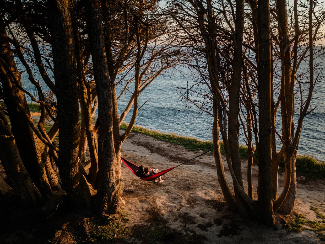 Couple sitting on a hammock between two trees at Davenport. Photographed by Ben Ingram