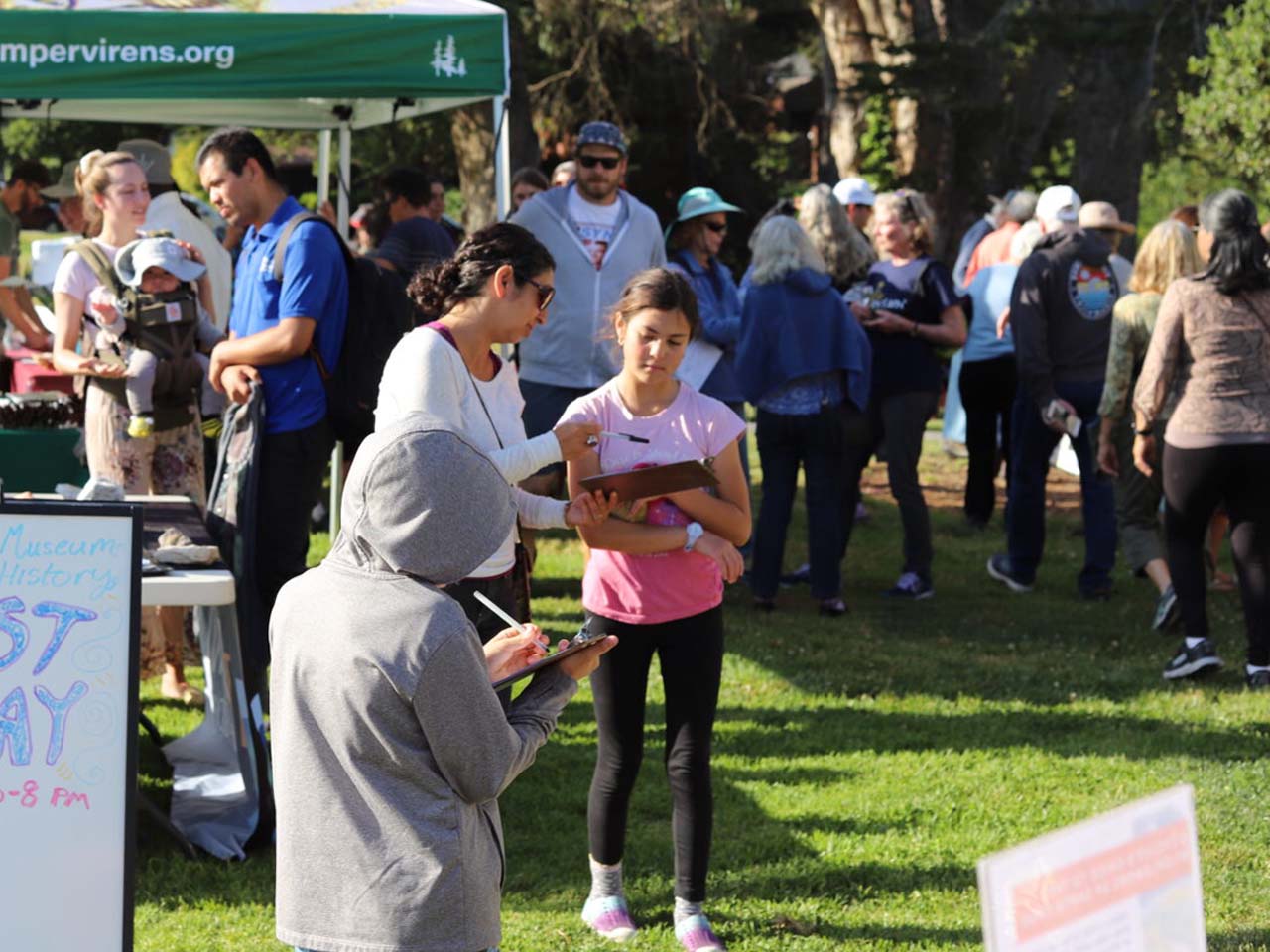 Museum attendees looking at outdoor vendor booths.