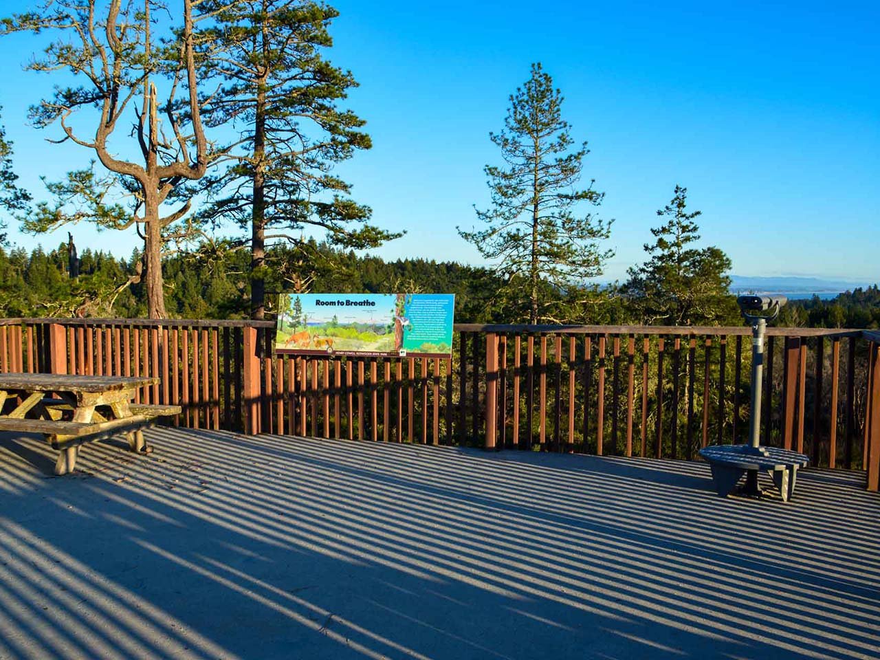 An image of a deck with a binoculars and a view of the ocean in the distance.