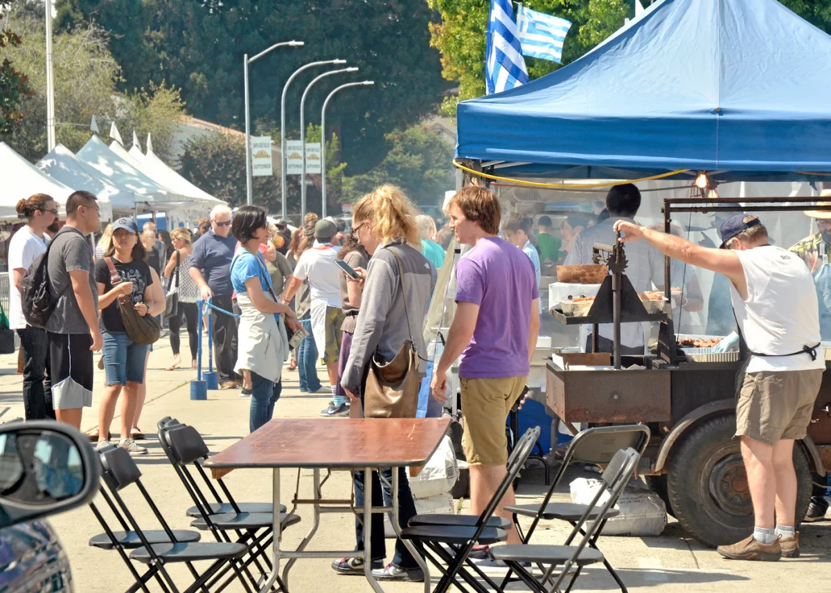 Gyro spit being turned as festival attendees explore food stalls