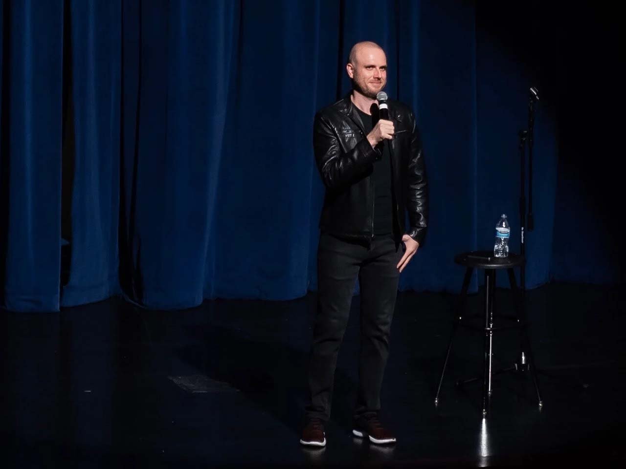 Comedian in front of a blue curtain