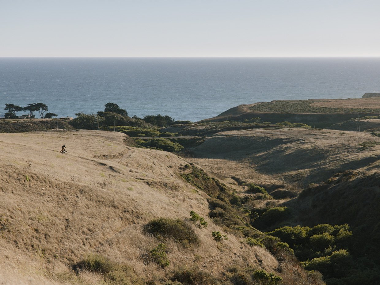 Mountain biker with a view of the ocean at Cotoni Coast Dairies. Photographed by Ben Ingram