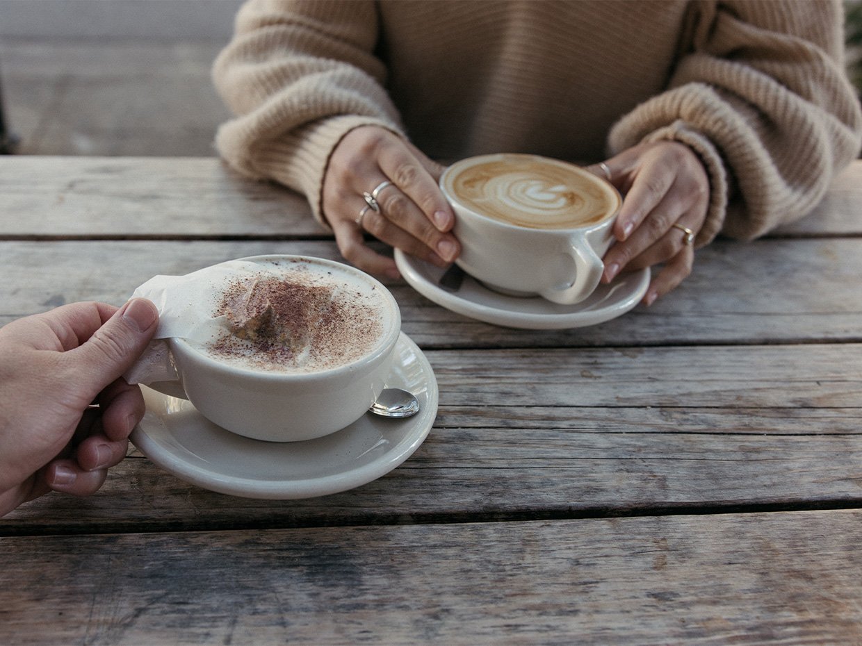 Two individuals holding cups of Bowl of Soul and a latte at Verve Downtown. Photographed by Ben Ingram