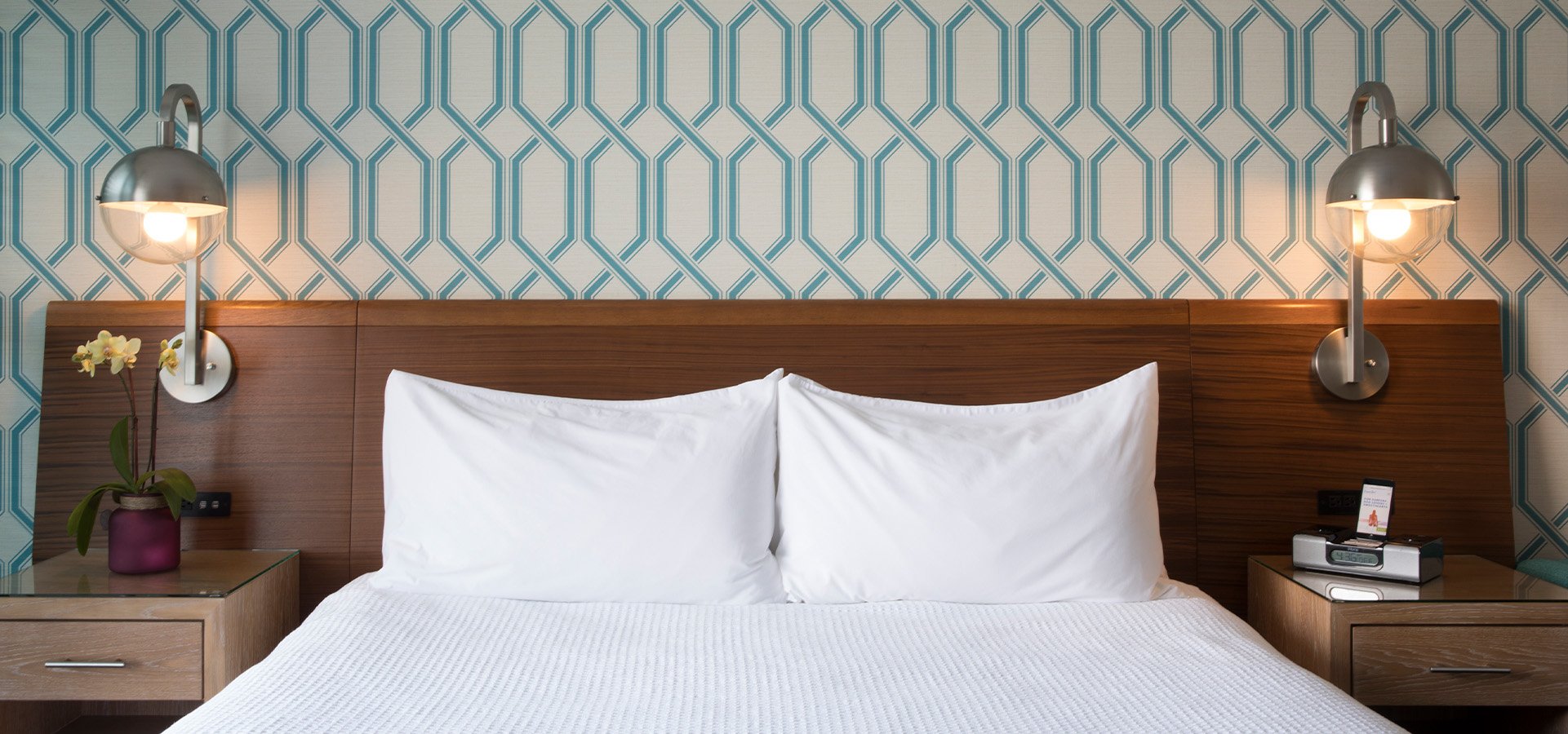 Guest room at Dream Inn, displaying the bedside sconce lights and wooden headboard