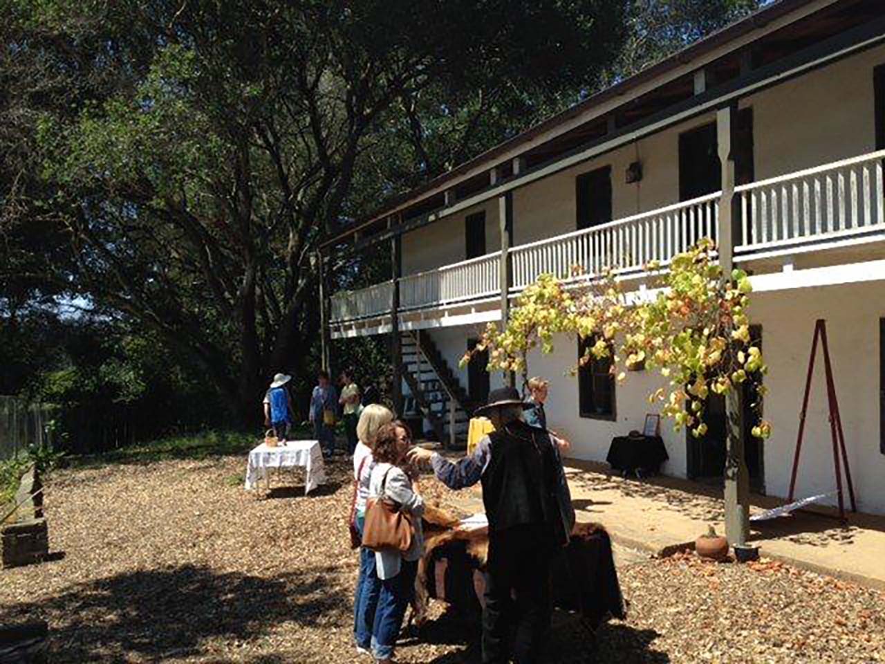 Families enjoying presentations outside a 2-story adobe hacienda
