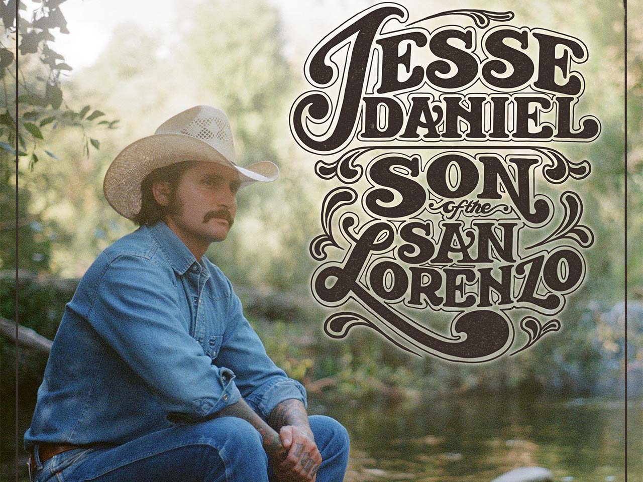 Jesse Daniel in a cowboy hat sitting by the San Lorenzo River