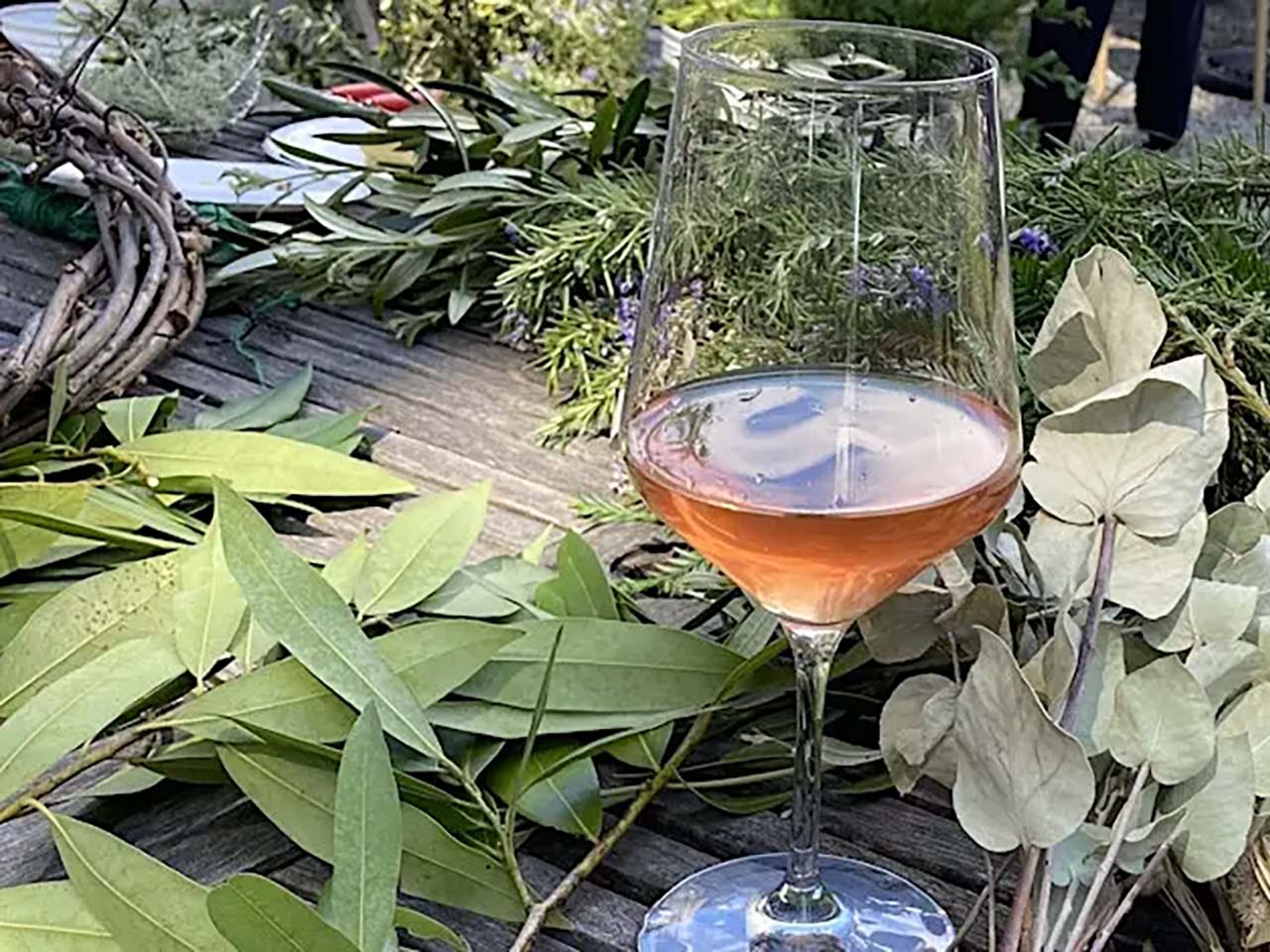 A glass of rose amid farm foliage