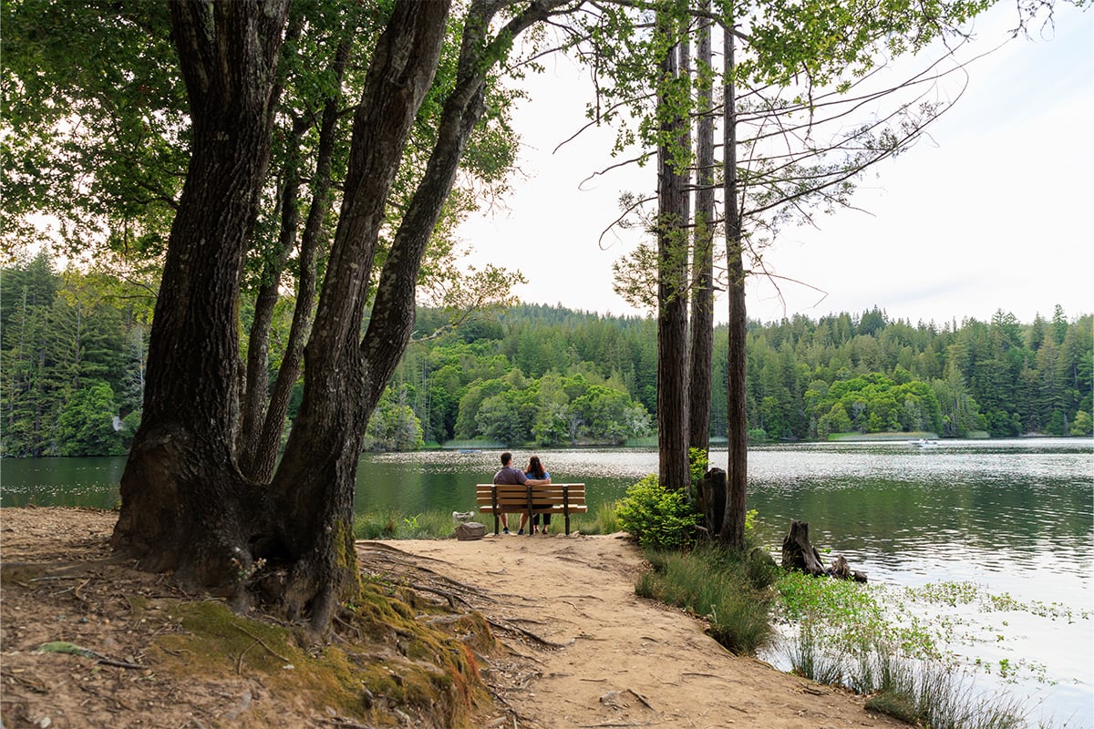 Two individuals sitting on a bench overlooking Loch Lomond. Photographed by Daniel Gorostieta