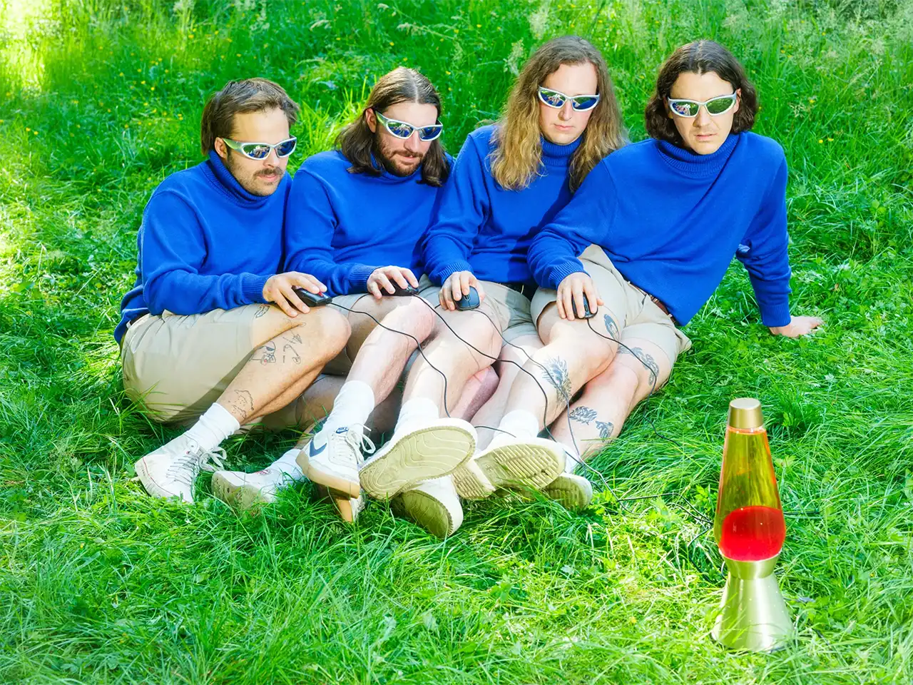 The band in matching blue long sleeves and khaki shorts, controlling a lava lamp with computer mouses