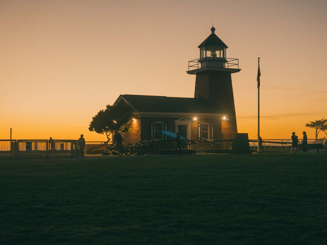 Brick lighthouse at sunset with a wide lawn in front
