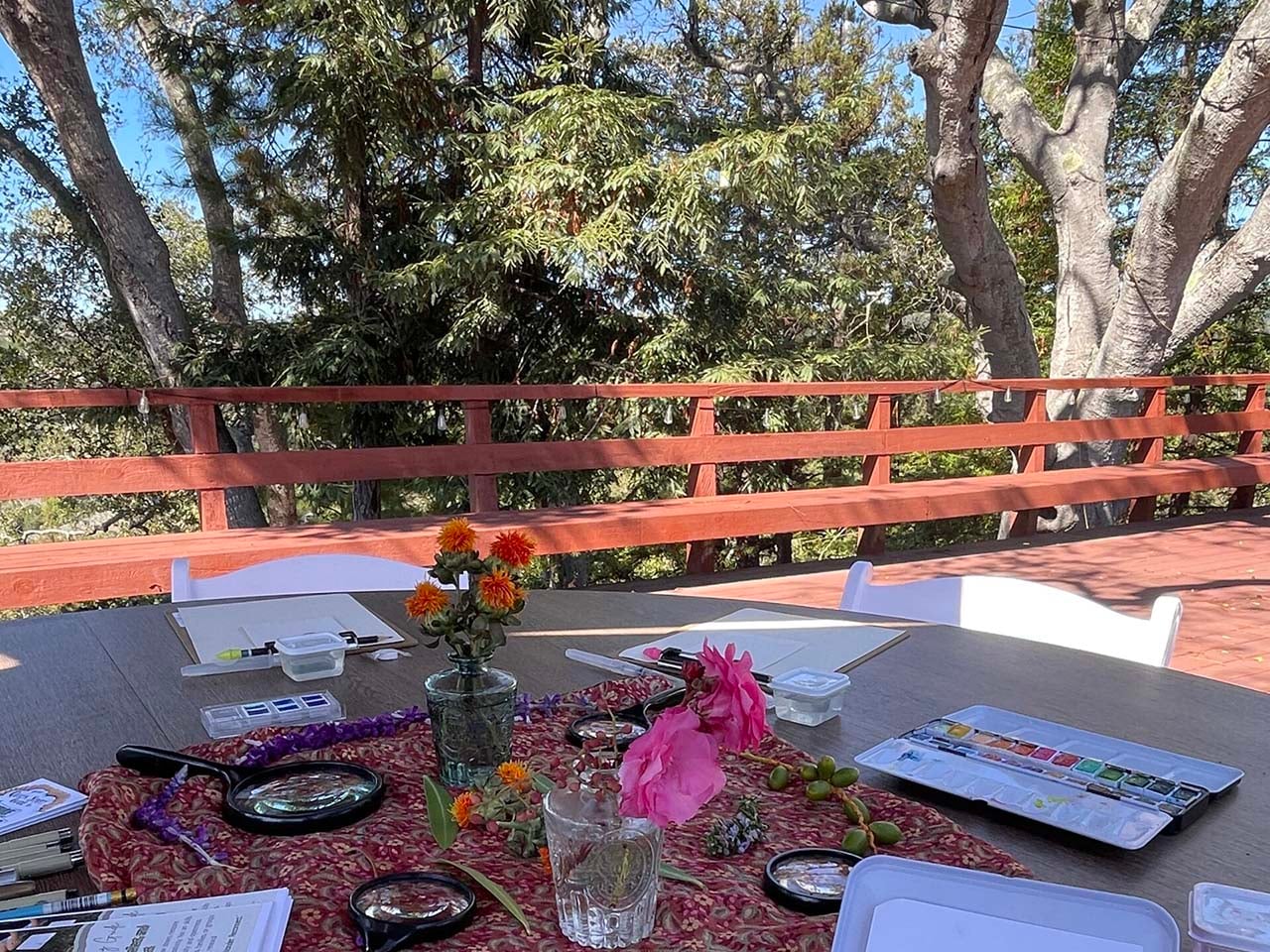 Art supplies on a table beneath a forest canopy