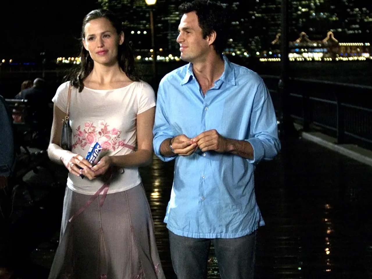 Couple on a boardwalk eating snacks.