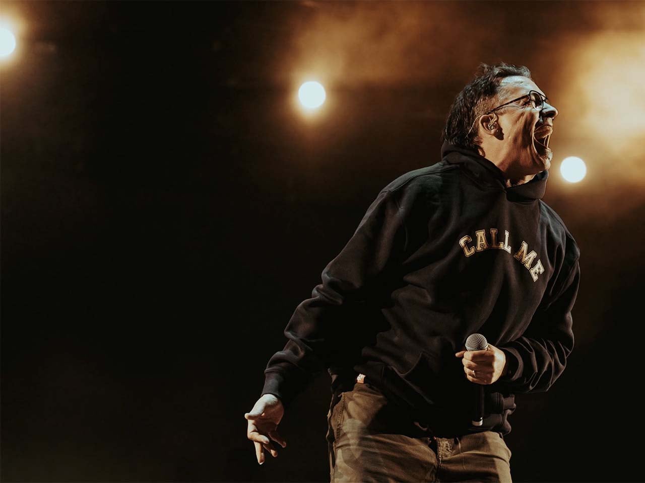 Ant of Atmosphere screaming into the crowd with lights behind him