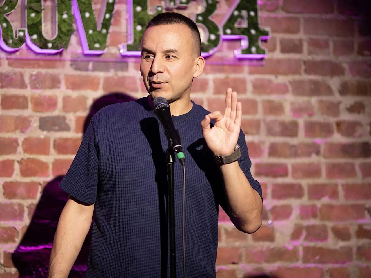 Comedian in front of a brick wall