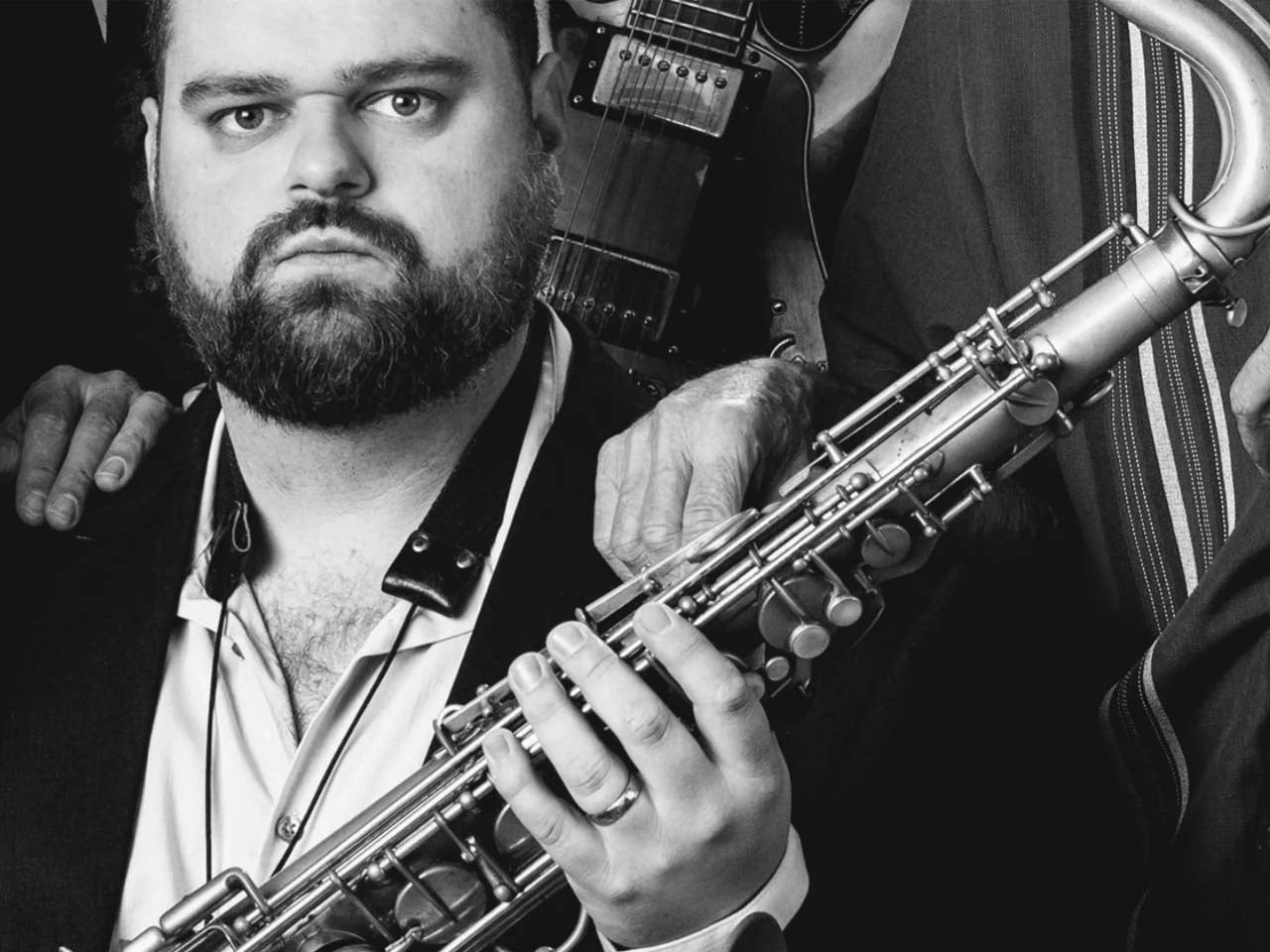 Black and white image of a somber man holding a saxophone