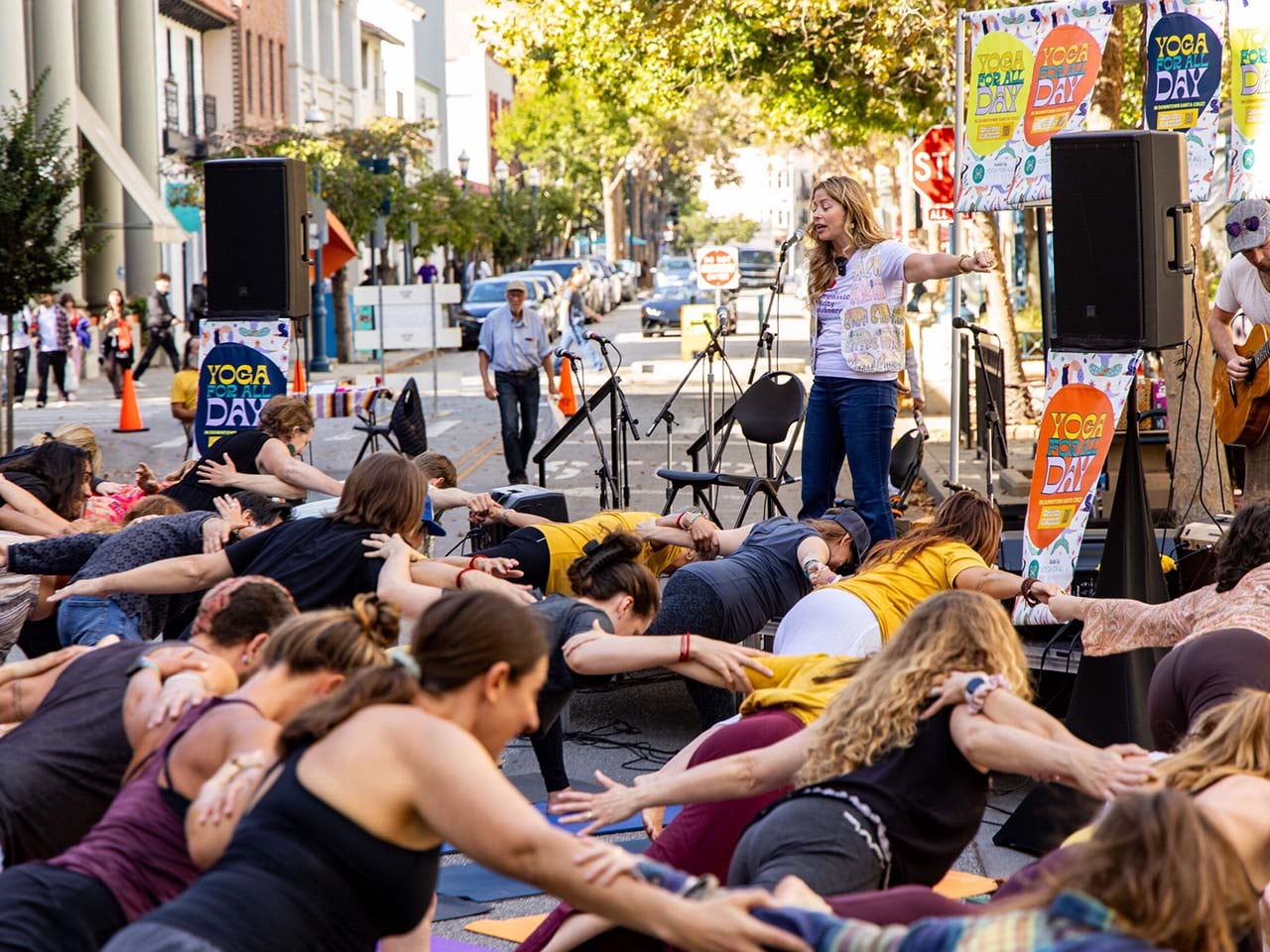 A bunch of people in the middle of downtown holding a yoga pose