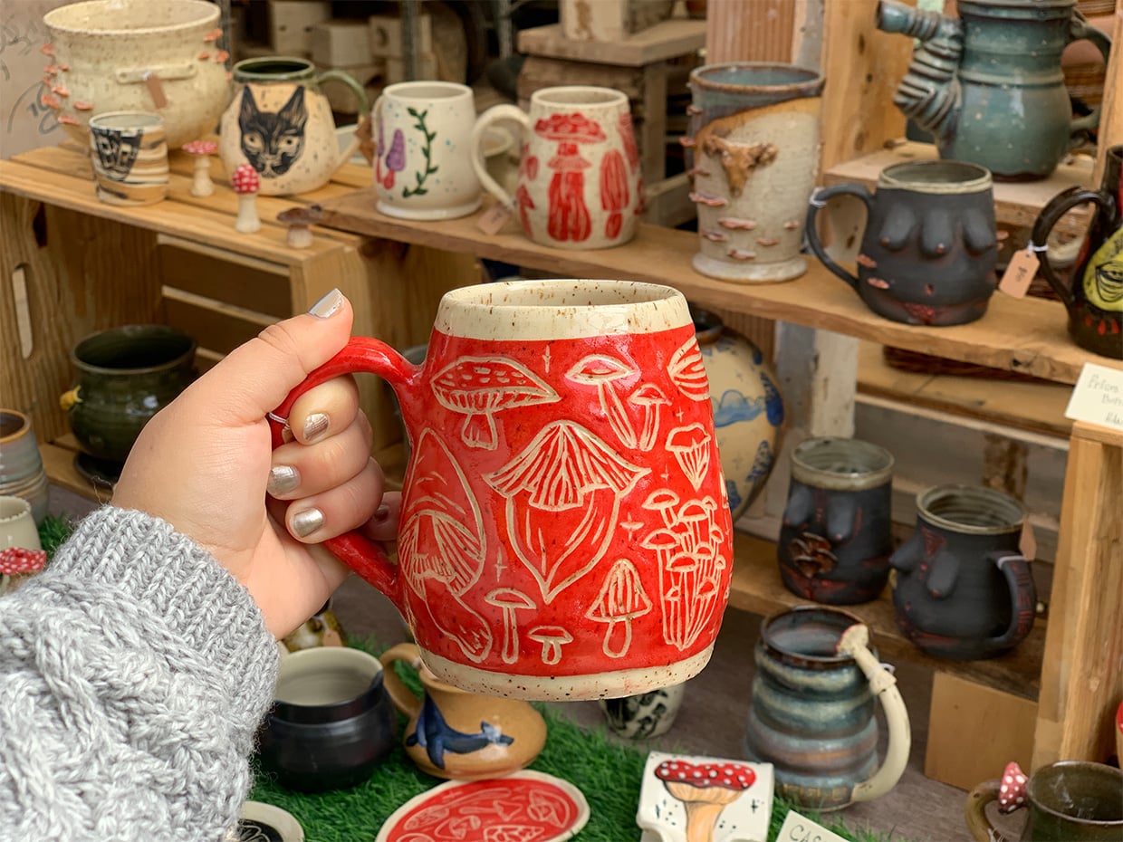 Ceramic Artist, Anna's, red mug held up at her Open Studios. Photographed by Monica Multer
