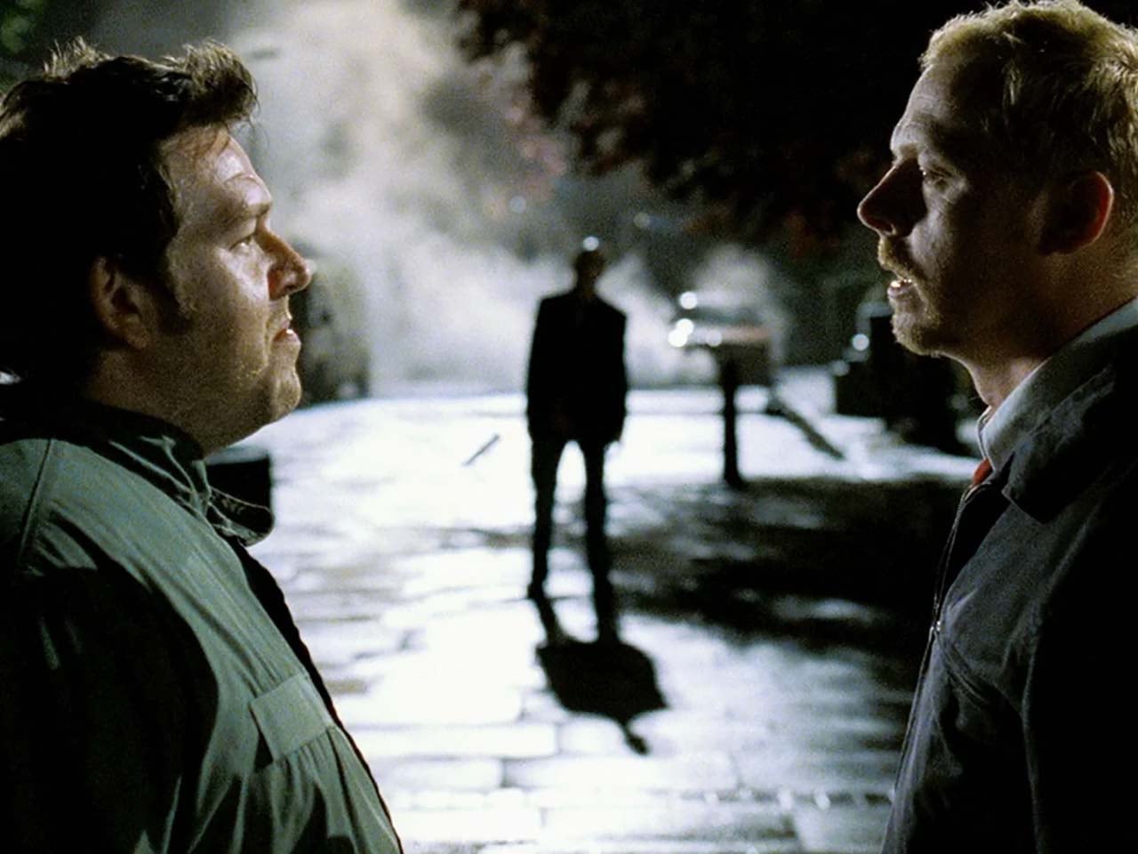 Townie slackers face each other in profile as a zombie steps through the fog between them.