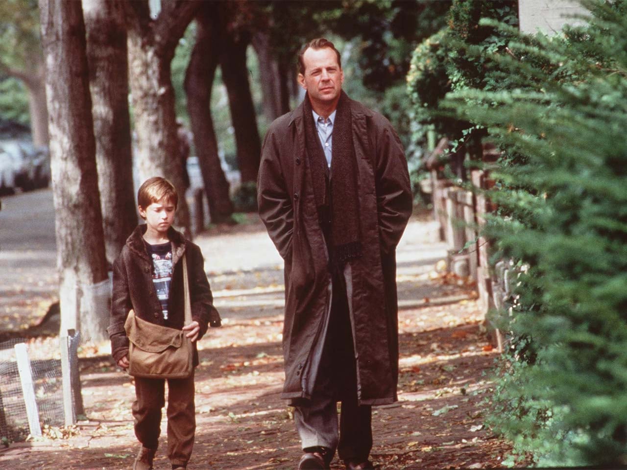 The characters of Dr. Malcolm Crow and Cole Sear walking down a treelined street that looks like downtown Santa Cruz