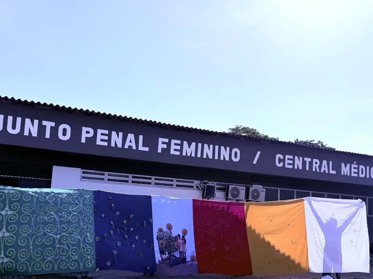 Silhouette of an artist putting up a cloth exhibition with the light behind them in front of a women's prison
