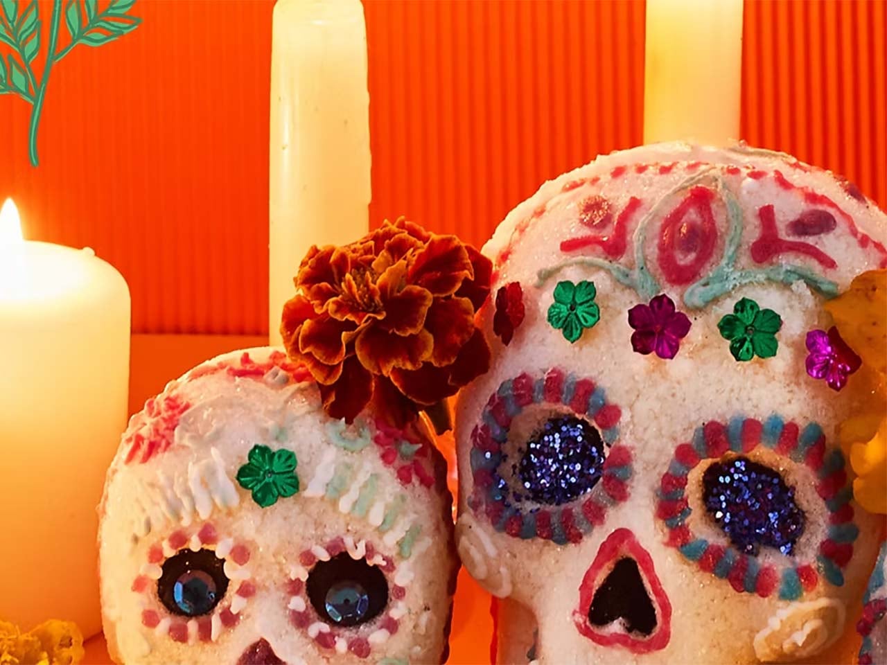 Sugar skulls with candles against an orange background